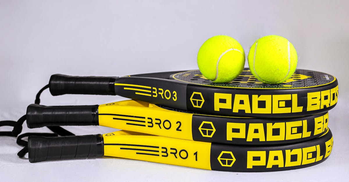 Vibrant padel rackets and tennis balls on white backdrop, ideal for sports themes.